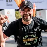 Piotr Łobodziński triumfuje na mecie maratonu, z dumą unosi pięści.