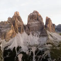 Majestatyczne **Tre Cime** w Dolomitach o wschodzie słońca. Skaliste szczyty i kręte ścieżki w otoczeniu surowego piękna.