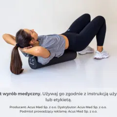 Kobieta leży na wałku do masażu, próbując rozluźnić mięśnie pleców.