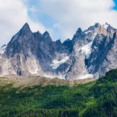 Majestatyczne szczyty Mont Blanc latem, z zielonymi zboczami i resztkami śniegu.