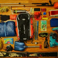 Zestaw sprzętu zimowego: narty, buty, kask, łopatka, kijki, plecak. Zobacz, jak przypiąć kijki do plecaka, by były pod ręką.
