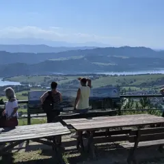 Widok z góry Wdżar na jezioro i góry. Grupa turystów podziwia panoramę.
