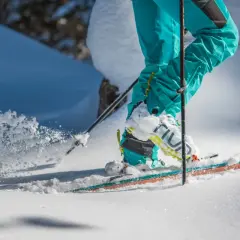 Narty i buty pod raki w akcji, śnieg wzbija się w powietrze.