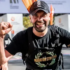 Piotr Łobodziński triumfuje na mecie maratonu, z dumą unosi pięści.