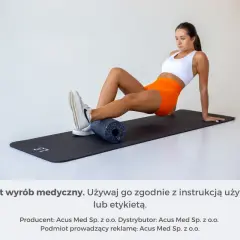 Kobieta wykonuje rolowanie po treningu, masując łydkę wałkiem na macie.
