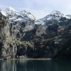 Majestatyczne Tatry w maju, z ośnieżonymi szczytami odbijającymi się w spokojnej tafli jeziora.