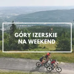 Trzech rowerzystów przemierza malownicze Góry Izerskie. W tle widać kolejkę gondolową i rozległą panoramę.