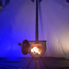 Wnętrze namiotu z palącym się piecykiem. To idealne ogrzewanie do namiotu, które tworzy przytulną atmosferę.