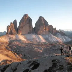 Dwie osoby podziwiają majestatyczne trzy siostry Dolomity o wschodzie słońca.