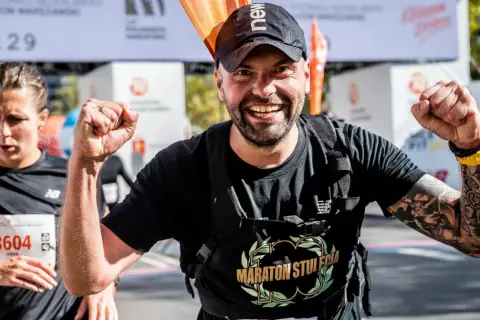 Piotr Łobodziński triumfuje na mecie maratonu, z dumą unosi pięści.