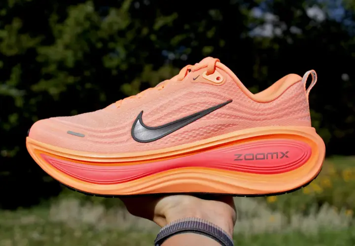 Pomarańczowe buty na bieżnię elektryczną z czarnym logo Nike i napisem ZoomX. Idealne do treningów.