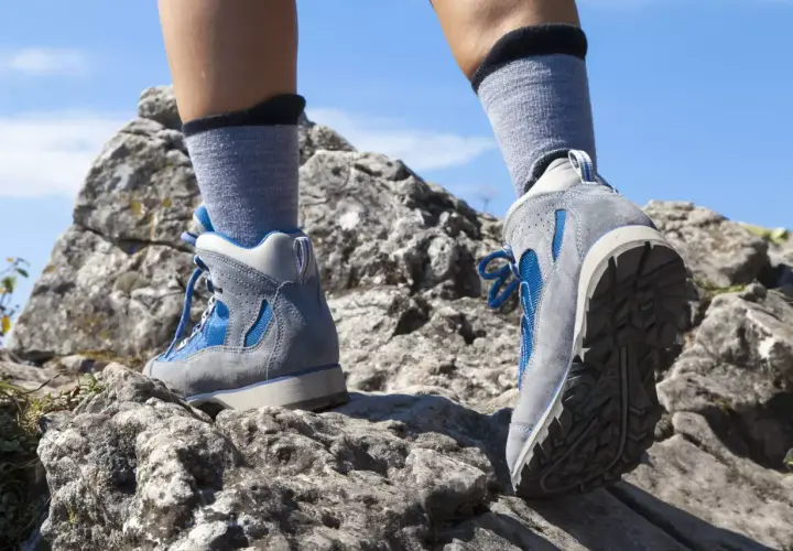 Nogi w butach trekkingowych i skarpety w góry stawiają pierwsze kroki na skalistej ścieżce.