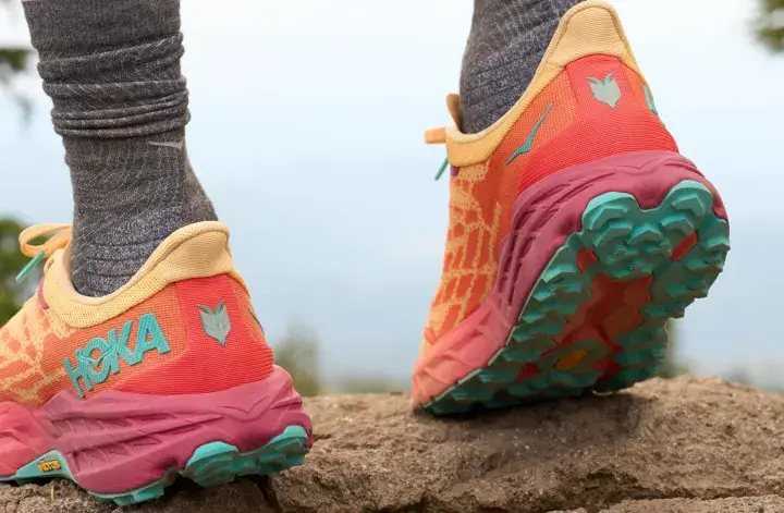 Kolorowe buty Hoka na kamienistym szlaku. Firma Hoka słynie z amortyzacji i innowacyjnych rozwiązań dla biegaczy.