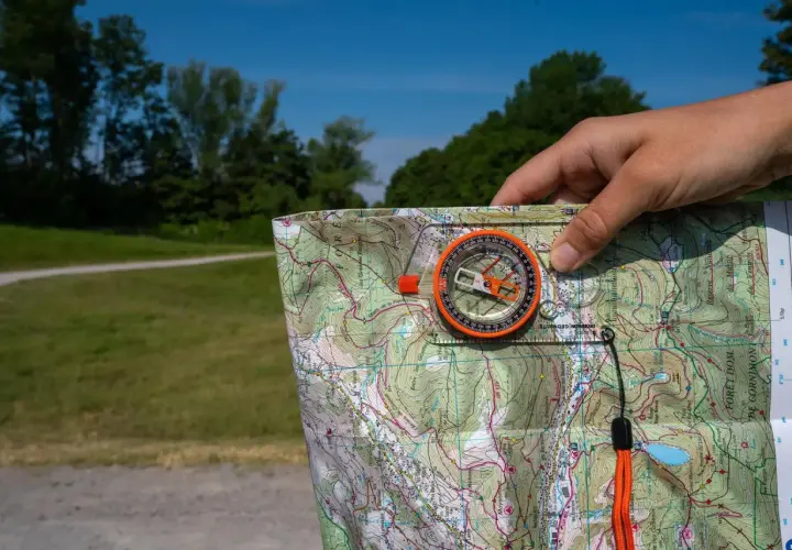 Biegi na orientację jak czytać mapę: kompas i mapa topograficzna w dłoni, gotowe do nawigacji w terenie.