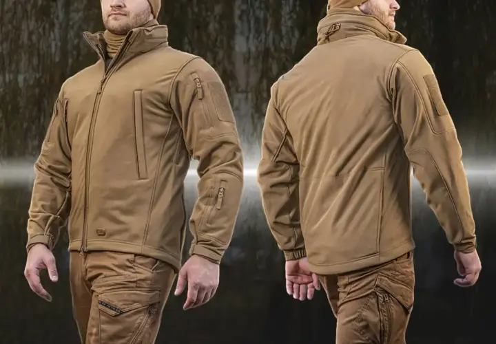Mężczyzna w beżowej kurtce taktycznej z materiału softshell. Kurtka ma liczne kieszenie i ściągacze.