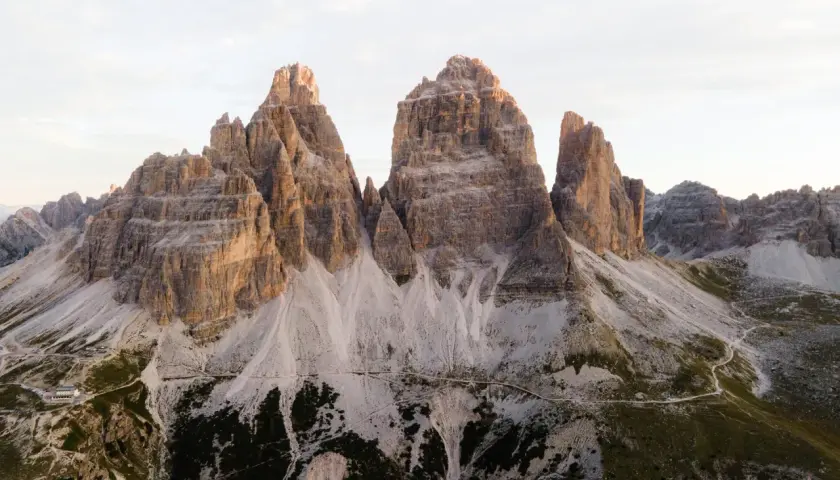 Majestatyczne **Tre Cime** w Dolomitach o wschodzie słońca. Skaliste szczyty i kręte ścieżki w otoczeniu surowego piękna.