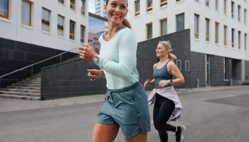 Dwie kobiety biegają po mieście, przygotowując się do treningu ultramaraton 50 km. Uśmiechnięte, pełne energii.