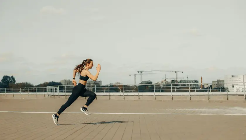 Kobieta w stroju sportowym biegnie po betonowym placu. To inspiracja dla każdego, kto szuka poradnika biegacza.