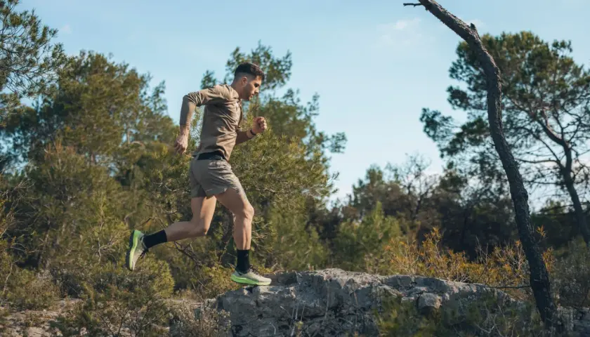 Mężczyzna w sportowym stroju biegnie po kamienistym terenie wśród drzew. To jego trening biegowy metodą Skarżyńskiego.