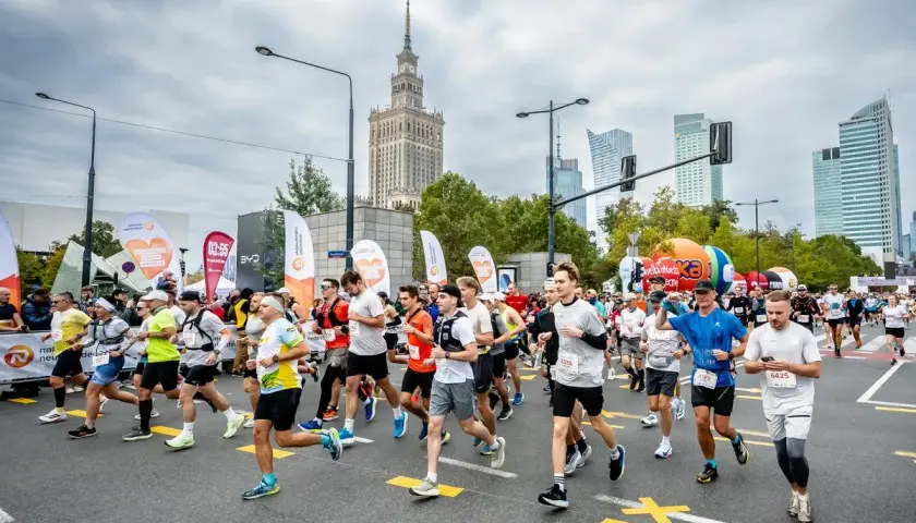 Uczestnicy biegną w maratonie, pokonując jego długość. W tle Pałac Kultury i Nauki.