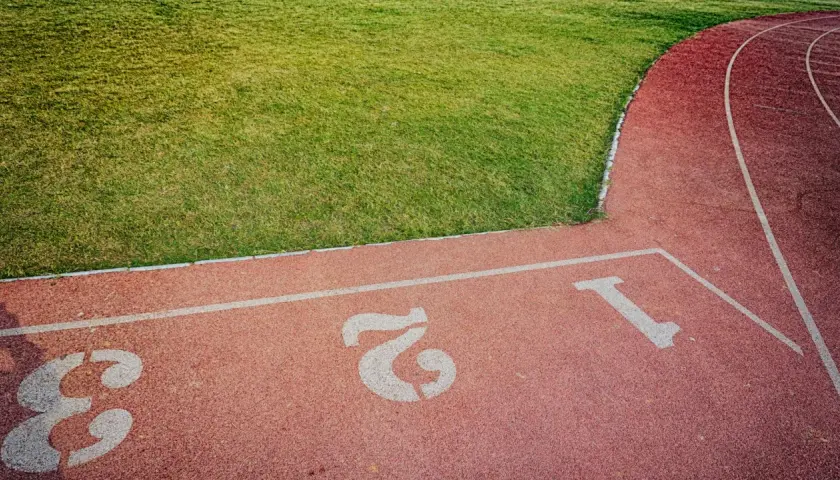 Bieżnia stadionu z numerami torów 1, 2, 3. Zielona trawa obok. Czas na 5 km!