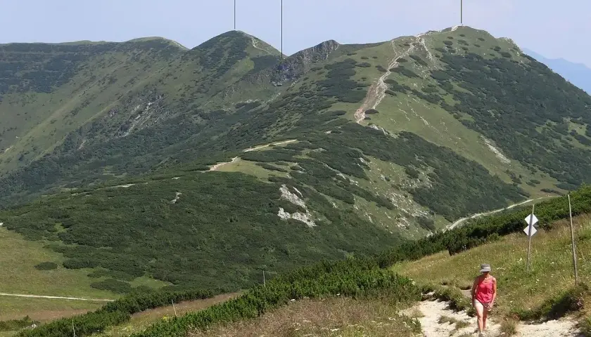 Widok na góry z turystką na szlaku. W oddali widać szczyt Chleb, Hromové i sedlo za Hromovým.