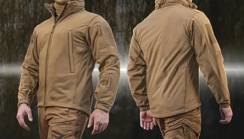 Mężczyzna w beżowej kurtce taktycznej z materiału softshell. Kurtka ma liczne kieszenie i ściągacze.