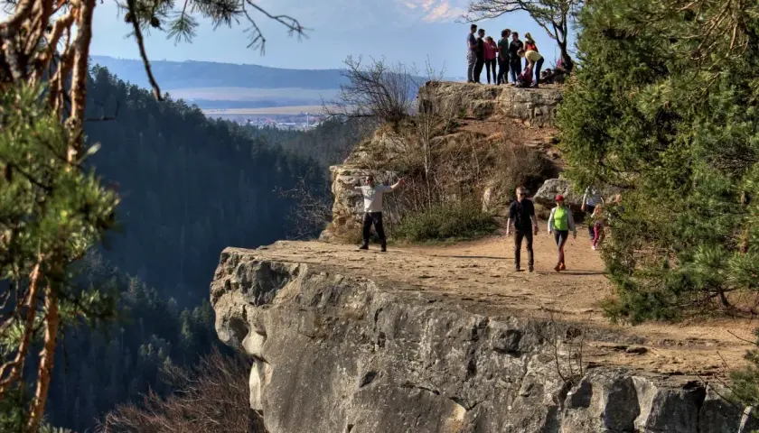 Grupa turystów podziwia widok na Tatry ze skalnego urwiska. To prawdziwy słowacki raj, pełen piękna i przygody.