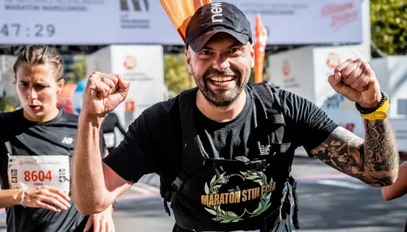 Piotr Łobodziński triumfuje na mecie maratonu, z dumą unosi pięści.