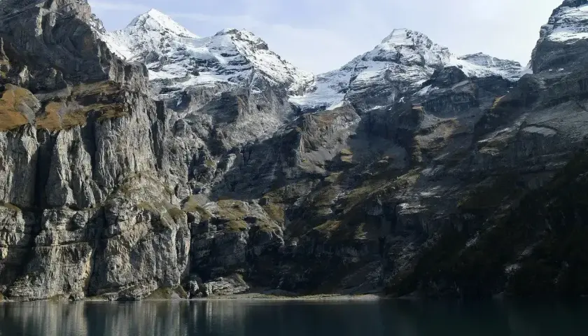 Majestatyczne Tatry w maju, z ośnieżonymi szczytami odbijającymi się w spokojnej tafli jeziora.