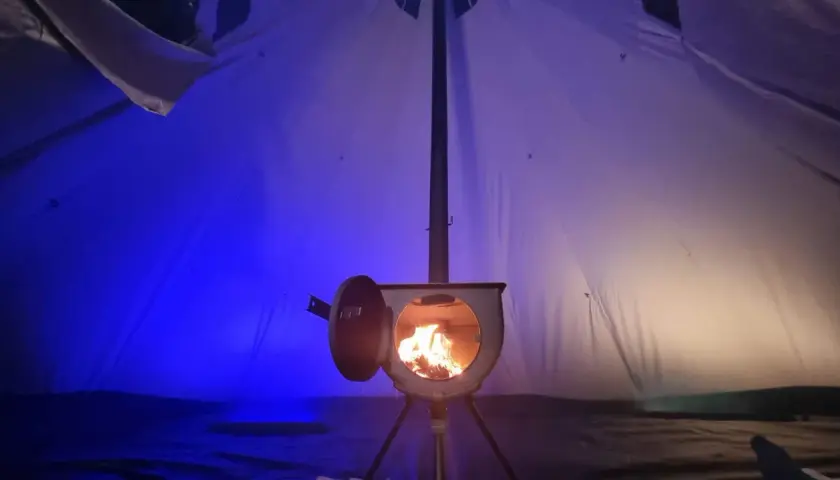 Wnętrze namiotu z palącym się piecykiem. To idealne ogrzewanie do namiotu, które tworzy przytulną atmosferę.