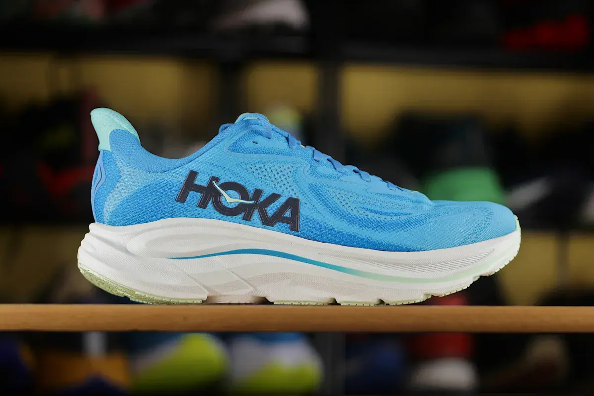 Niebieskie buty sportowe Hoka z charakterystycznym logo. To firma znana z innowacyjnych rozwiązań w obuwiu biegowym.