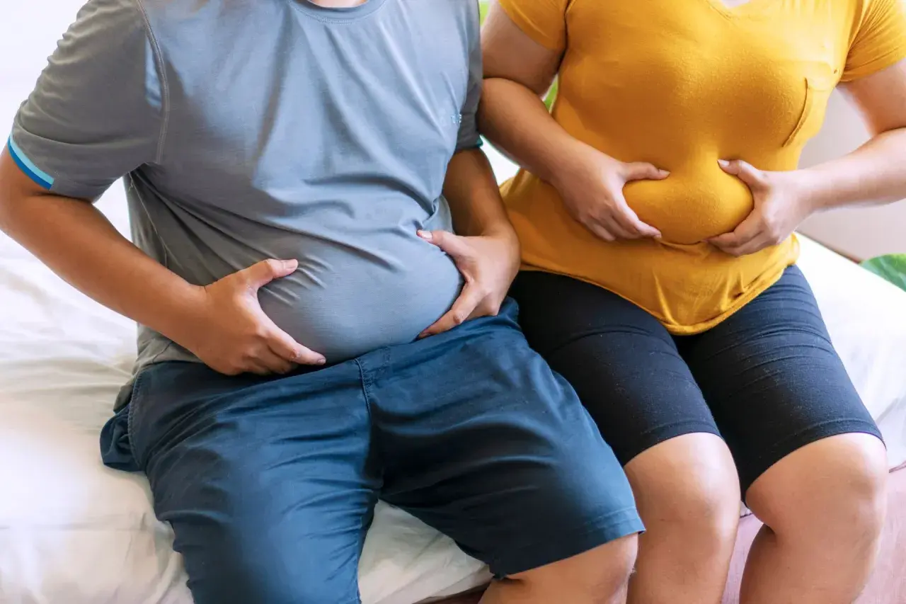 Osoby z nadwagą trzymają się za brzuchy. Zastanawiają się, czy bieżnia odchudza brzuch.
