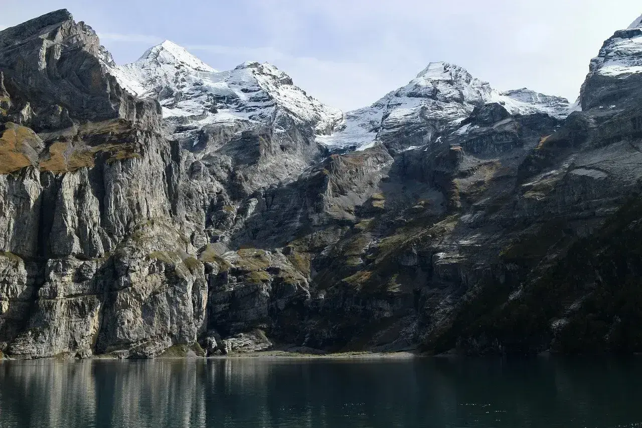 Majestatyczne Tatry w maju, z ośnieżonymi szczytami odbijającymi się w spokojnej tafli jeziora.