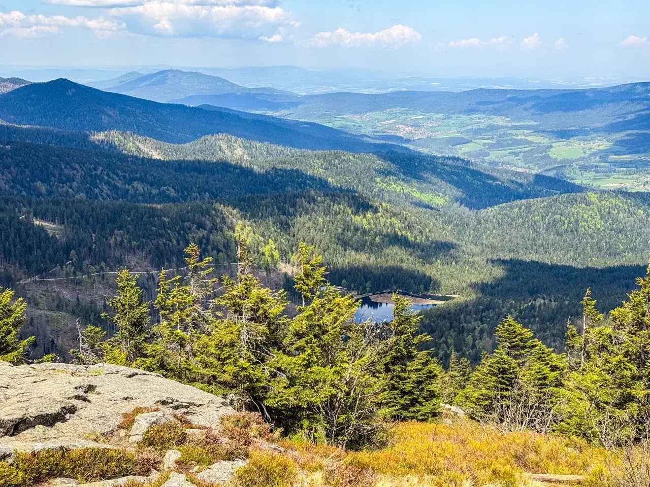 Widok na malownicze góry w Czechach, zalesione zbocza, jezioro i dolina w oddali.