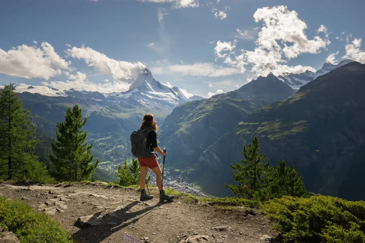 Turystka z plecakiem podziwia majestatyczny Matterhorn, kontynuując swoją podróż po szlaku Haute Route.